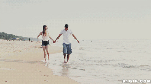 情侣赤脚牵手漫步沙滩图片