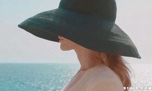 女子戴遮阳帽海边散步图片