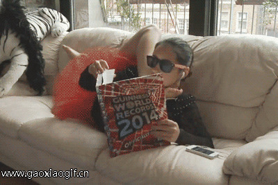 戴着墨镜的女孩趴在沙发上看杂志gif图片:看书