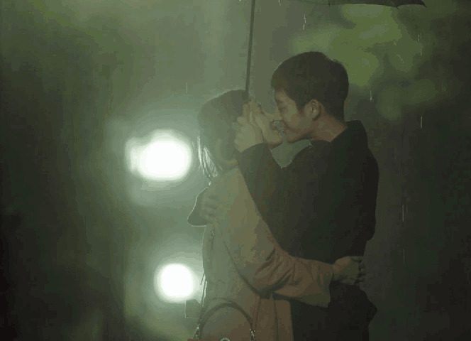 情侣在大雨中打着雨伞亲吻GIF动态图