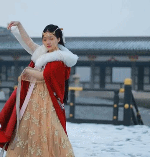 美丽的姑娘穿着绣花的披风在雪中跳舞GIF动态图