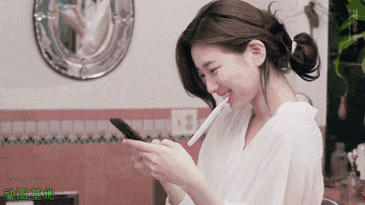女神刷着牙拿着手机聊天满脸的微笑gif图片:聊天