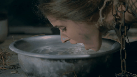 一位被铁链锁住的女人跪在地上喝水GIF图片:喝水