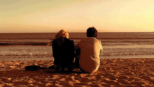 一对恩爱的情侣坐在海边看浪花gif图片