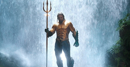 拿着金叉的勇猛男人在瀑布下站着很霸气的样子gif图片:霸气