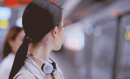 脖子里戴着耳机的漂亮女孩在车站等车gif图片:女神