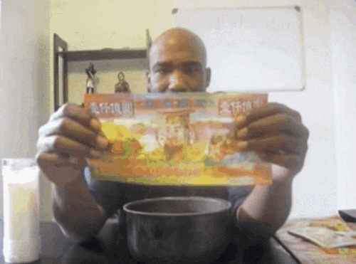 一位黑人拿出一张冥钞在手中玩耍gif图片