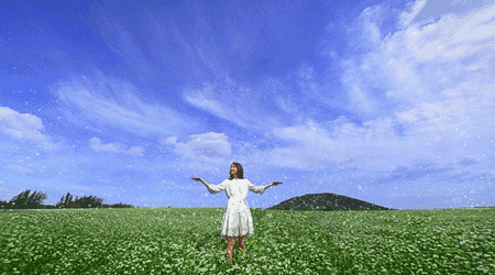 美丽的姑娘穿着白裙子在草原上看蓝天白云gif图片