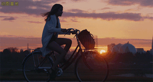 夕阳西下女孩独自一人骑着骑自行车回家gif图片