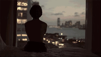 女孩坐在床边看窗外的夜景gif图片